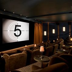 an empty movie theater with chairs and tables in front of the screen that is projected on the wall