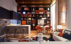 a living room filled with furniture next to a kitchen and dining room table in front of a brick wall