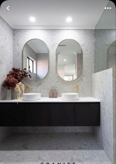 two round mirrors are on the wall in this modern bathroom with double sinks and marble countertops