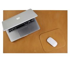 an apple laptop computer sitting on top of a wooden desk next to a mouse pad