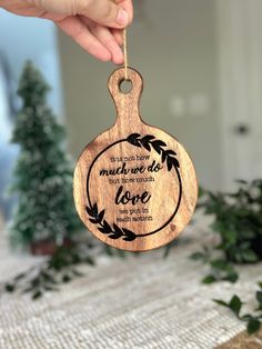 a hand holding a wooden ornament with the words, much love is written on it