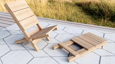 a wooden chair and footstool sitting on top of a tile floor next to a grassy field