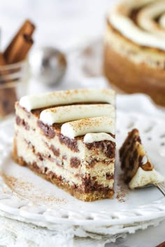 a piece of cake on a plate with a fork and cinnamon roll in the background