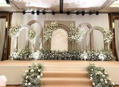 the wedding stage is decorated with white flowers and greenery