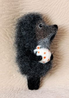 a needled animal that is laying down on a blanket with its head in the shape of a bear