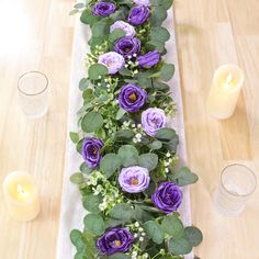 the table is set with purple flowers and greenery on it, along with candles