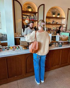 a woman standing in front of a counter at a coffee shop