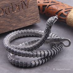 Elevate your style with this Viking Ouroboros vintage snake bracelet, a symbol of eternal cycles and timeless fashion. Crafted from high-quality stainless steel, this necklace exudes durability and style. Choose from three lengths: 50cm, 60cm, or 70cm, or opt for private custom sizing for the perfect fit. Packaged with care, each necklace comes with a black jewelry bag and a wooden box, making it an ideal gift for the fashion-forward individual in your life. Embrace the spirit of Viking heritage Snake-shaped Metal Bracelets As Gifts, Engraved Metal Snake-shaped Jewelry, Silver Metal Snake Bracelets, Silver Metal Snake Bracelet, Silver Snake-shaped Bracelet As Gift, Silver Snake-shaped Bracelet For Gift, Silver Snake-shaped Bracelets For Gifts, Vintage Snake-shaped Jewelry Gift, Vintage Snake Jewelry For Gifts