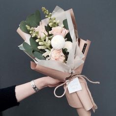 a person holding a bouquet of flowers in their hand with a tag tied around it