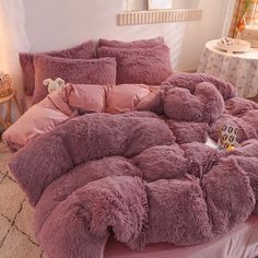 a bed covered in pink fluffy blankets and pillows