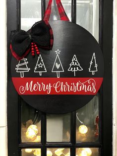 a merry christmas sign hanging on a door with lights in front of it and a bow at the top