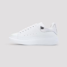 Alexander McQueen White Leather Sneakers. Pure white leather sneakers, round toe, top lace-up fastening, silver-tone printed logo on the tongue, perforated details on the upper, silver tone detail on the heel, back white logo on the heel, white rubber sole. Modern Silver Sneakers With Metallic Logo, Silver Low-top Sneakers With Metallic Logo, Silver Casual Sneakers With Metallic Logo, Silver Low-top Sneakers With Rubber Sole, Silver Lace-up Sneakers With Metallic Logo, Silver Leather Sneakers With Contrast Sole, Silver Sneakers With Metallic Logo For Streetwear, Classic Silver Sneakers For Streetwear, Streetwear Sneakers With White Sole And Metallic Logo