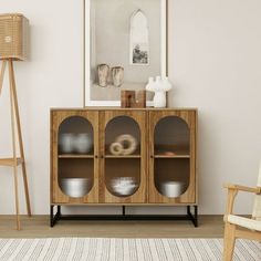 a wooden cabinet with glass doors in a living room next to a chair and lamp