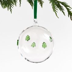 a glass ornament hanging from a christmas tree with green trees painted on it