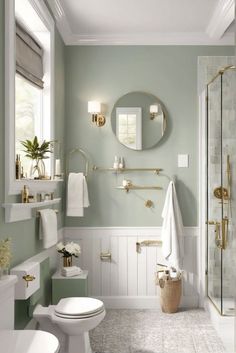 a white bathroom with green walls and gold fixtures on the shower, toilet and sink