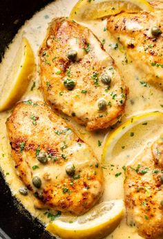 chicken with lemons and capers in a white sauce on a black skillet