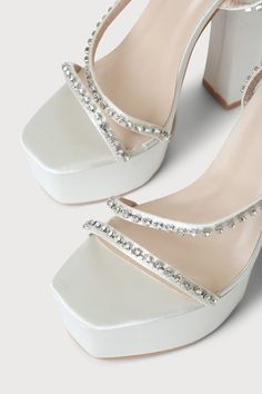 Lulus Exclusive! Feel like you're stepping out onto the stage in the Lulus Sinia Ivory Satin Rhinestone Platform High Heel Sandals! Sleek satin shapes these statement-making heels that have a square toe footbed atop a 1.75"" toe platform. Clear rhinestones, in silver settings, adorn the toe strap, vamp strap, and the matching wrapping ankle strap that secures with a silver buckle. 5. 5" wrapped black heel. Cushioned insole. Felted rubber sole has nonskid markings. Man made materials. Imported. L Satin Heels With Rhinestones For Prom, Embellished Synthetic Sandals For Wedding, White Satin Evening Sandals, Glamorous Embellished Satin Heels, Glamorous Synthetic Sandals For Wedding, Rhinestone Synthetic Heels For Wedding, Wedding Heels With Rhinestones In Synthetic Material, Glamorous Satin Heels For Prom, Satin High Heels