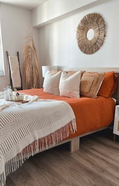 a bed with an orange blanket and white pillows