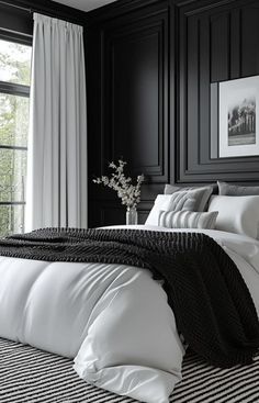 a black and white bedroom with striped bedding, pillows and throw blankets on the bed