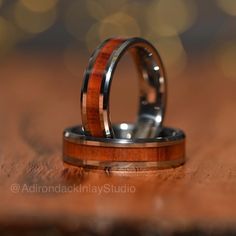 two wedding rings with wood inlays on a wooden surface, close up view