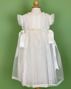 An elegant off-white dress that has a gorgeous detail in smock on the front with delicate laces. The dress has two satin ribbons on the side, and has buttons on the back for closure. Made in Spain Dry Clean Final sale, no exchanges nor returns are accepted Elegant Lace Patchwork Dress For Ceremony, Elegant Dresses With Lace Patchwork For Ceremony, Elegant Sleeveless Gown For Confirmation, Elegant Dress With Lace Sleeves For Confirmation, Elegant Confirmation Dress With Lace Sleeves, Elegant Ceremony Dress With Lace Patchwork, Elegant White Gown With Lace Trim, White Dress With Lace Sleeves And Fitted Bodice, White Sleeveless Dress For Ceremony