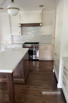 an empty kitchen with white cabinets and wood floors