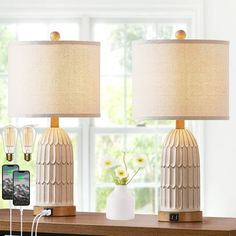 two lamps sitting on top of a wooden table next to a phone and other items