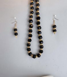 Black round glass beads accented with gold bead caps, comes with matching earrings. Necklace is 11" long, earrings are 1 1/2" long and come with soft gel backs for extra comfort. Jewelry is also glued at ends to give extra protection. Jewelry comes packaged in black jewelry box with soft white pad, and 3" x 5" organza bag. Thanks for shopping at an American Shop. Gold Elegant Beaded Earrings With Large Beads, Elegant Gold Beaded Earrings With Large Beads, Black Beaded Necklace With Gold Beads For Party, Elegant Black Beads With Gold Details, Traditional Black And Gold Beads, Black Dangling Beads Jewelry For Festive Occasions, Black Faceted Bead Earrings For Gift, Black Faceted Beads Earrings For Gift, Black Jewelry With Dangling Beads For Festive Occasions