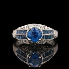 an antique sapphire and diamond ring with two blue stones in the center, on a black background