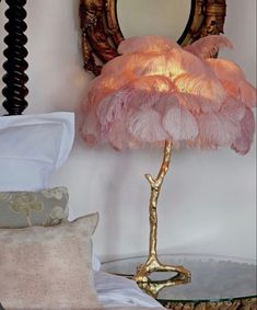 a pink lamp sitting on top of a glass table next to a mirror and pillows