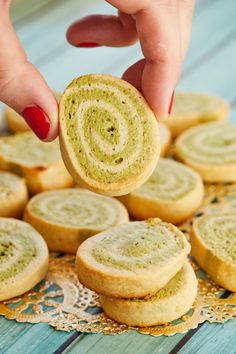 a person is picking up some cookies from a plate on a table with lace doily