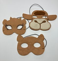 three masks are shown on a white surface, one has a dog's face and the other has a cat's head