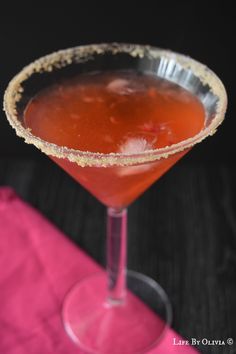 a close up of a cocktail in a coupe glass on a table with a pink napkin