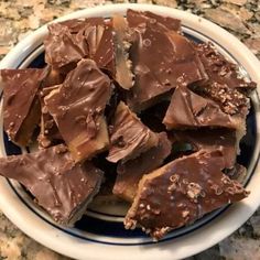 a white bowl filled with chocolate pieces on top of a counter next to a blue and white plate