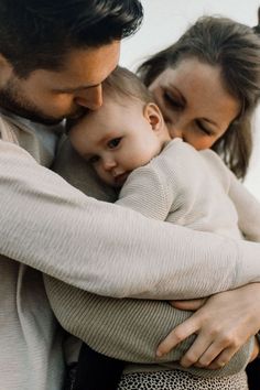 a man and woman holding a baby in their arms