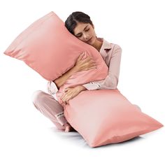 a woman sitting on the floor with pillows in front of her and she is covering her face