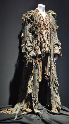 an old coat is on display in a museum exhibit with black cloths and other items