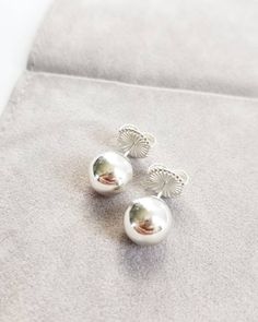 To find the pearl that is hidden...you must dive below. This extra large pair of sterling silver sphere studs are a great classic pair that can be worn as a companion pair with your other favorite studs, or worn alone. Custom finished in your choice of a soft, matte brushed finish, or a glossy, high polished finish, this timeless pair is versatile and chic. Similar to the look of pearls, but in metal! Large and dynamic, they are beautiful and go with just about anything! Large sterling silver bu Sterling Silver Sphere Earrings, Silver Orb Earrings For Gift, Silver Minimalist Pearl Earrings, Minimalist Sterling Silver Sphere Earrings, Elegant Silver Orb Earrings, Minimalist Sterling Silver Pearl Earrings In Silver, Minimalist Silver Sterling Silver Pearl Earrings, Ball Earrings, The Pearl