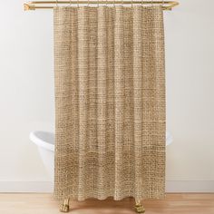 a beige shower curtain hanging on a wooden rail in front of a white bathtub