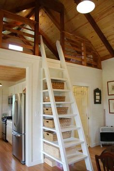 a ladder is in the middle of a kitchen with baskets on the floor and shelves below it