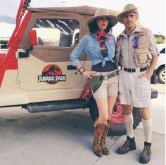 a man and woman are standing in front of a jeep with their hats on, posing for the camera