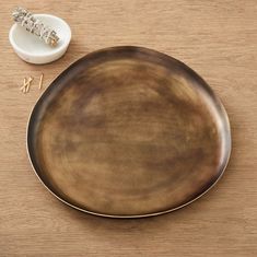 a brown plate sitting on top of a wooden table next to a small white bowl