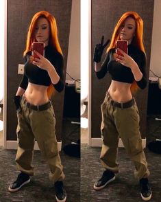 a woman with orange hair taking a selfie in front of a mirror wearing cargo pants