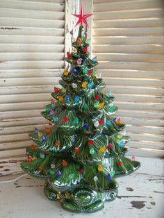 a green ceramic christmas tree sitting on top of a white table next to a window