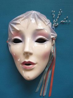 a white mask with beads on it's head and a tassel hanging from the side