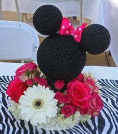 there is a flower arrangement with minnie mouse on top of the head and zebra print table cloth