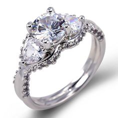 three stone engagement ring with diamond accents on the sides and an oval shaped center surrounded by round brilliant cut diamonds