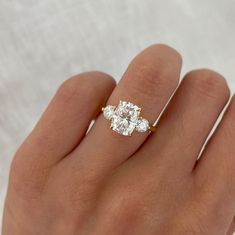 a woman's hand with three stone engagement ring on top of her left hand