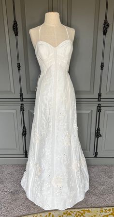 a white wedding dress on display in front of a gray wall