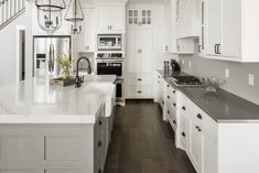 a large kitchen with white cabinets and black counter tops, along with dark wood flooring